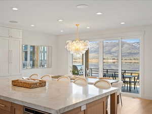 Kitchen with light stone counters, hanging light fixtures, a chandelier, plenty of natural light, and recessed lighting
