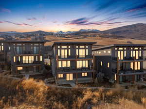 Rear view of property featuring a mountain view, a balcony, and a patio