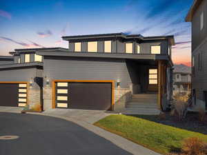 Modern home with stone siding, board and batten siding, an attached garage, and concrete driveway
