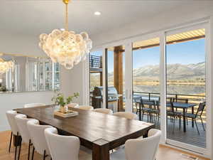Dining room with light wood finished floors, a chandelier, a water and mountain view, and recessed lighting