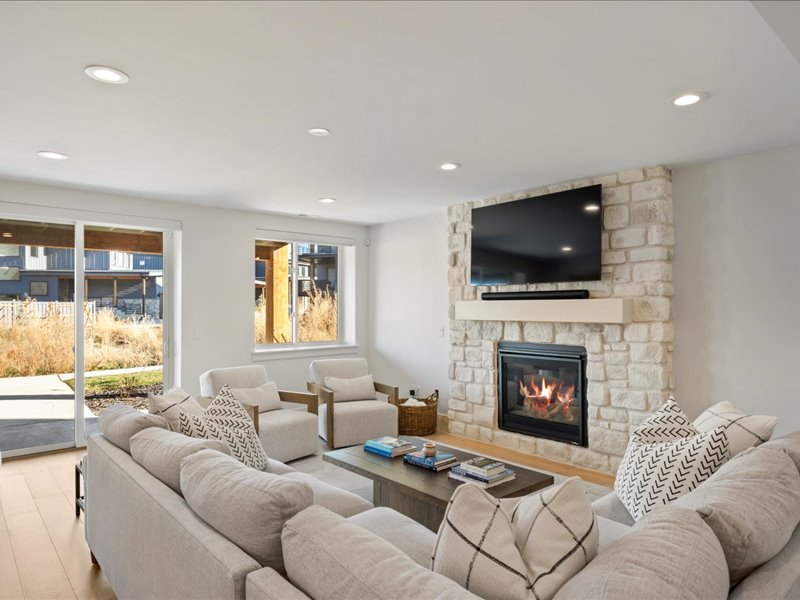 Living room with a stone fireplace, light wood-style floors, and recessed lighting