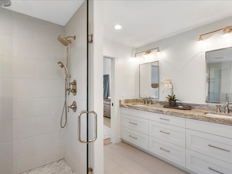 Full bath with a stall shower, double vanity, and light tile patterned floors