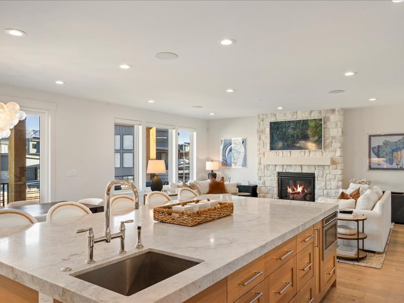 Kitchen featuring a fireplace, light stone counters, open floor plan, light wood-style flooring, and recessed lighting