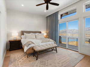 Bedroom with access to exterior, light wood finished floors, a water and mountain view, recessed lighting, and ceiling fan