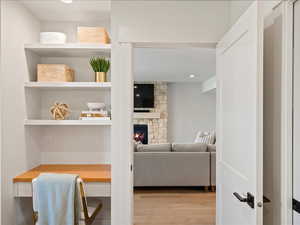 Living room with a stone fireplace, light wood-style flooring, and recessed lighting
