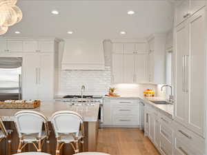 Kitchen featuring a breakfast bar area, light wood-style flooring, light stone counters, tasteful backsplash, and recessed lighting