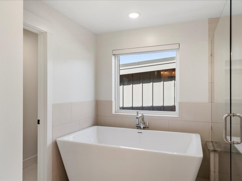 Bathroom with a freestanding bath, a shower stall, and tile walls