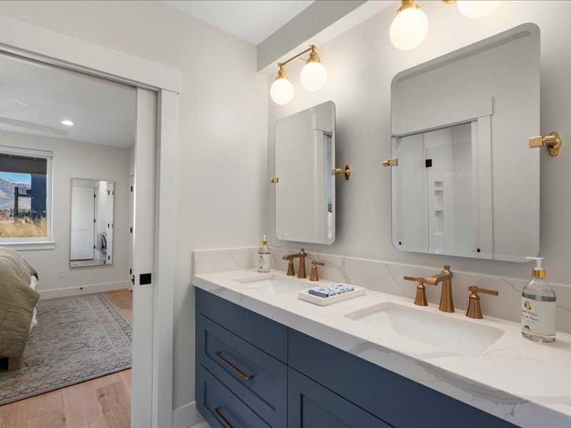 Ensuite bathroom with double vanity and light wood-style flooring