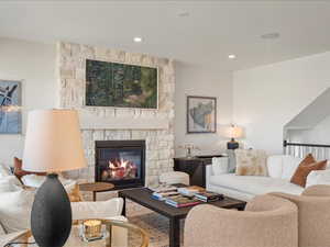 Living room with a stone fireplace and recessed lighting