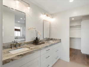 Bathroom with double vanity, a spacious closet, recessed lighting, and light tile patterned floors