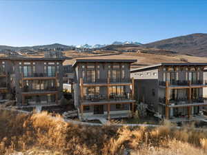 Back of property with a deck with mountain view, a patio, and a sunroom