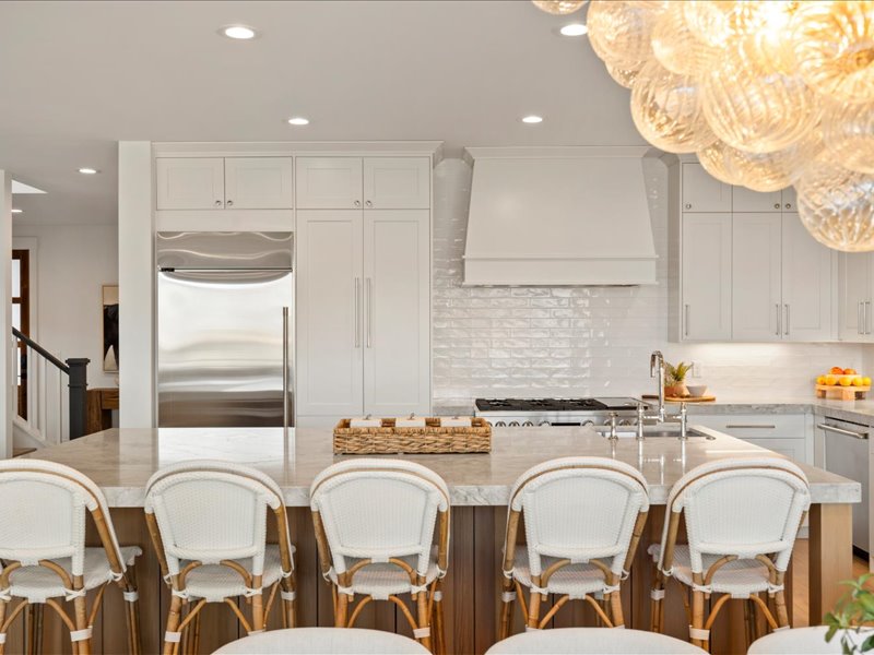 Kitchen with a breakfast bar area, stainless steel appliances, light stone counters, an island with sink, and recessed lighting