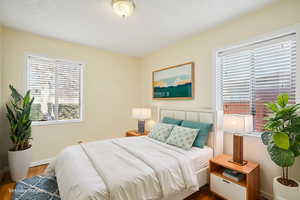 Bedroom with wood finished floors and multiple windows