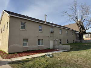 Back of house featuring a yard and stucco siding