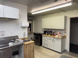 Kitchen featuring light floors, white cabinets, stainless steel appliances, and light countertops
