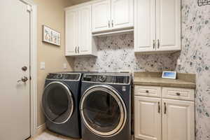 Laundry area featuring washer and clothes dryer and cabinet space