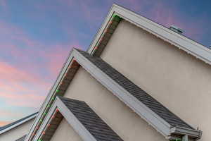 View of side of home with stucco siding and a shingled roof