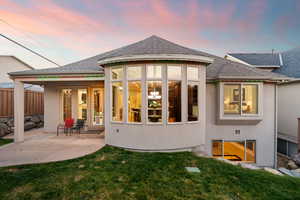 Back of property with roof with shingles, stucco siding, and a patio area
