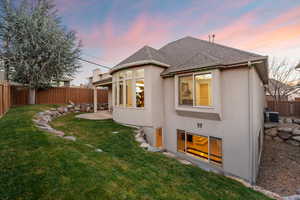 Back of house featuring a fenced backyard, roof with shingles, stucco siding, and a patio