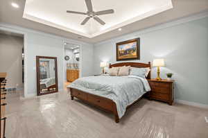 Bedroom featuring a tray ceiling, ensuite bathroom, recessed lighting, a ceiling fan, and crown molding