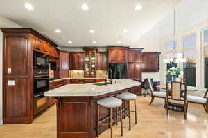 Kitchen featuring a breakfast bar area, light wood-style flooring, a kitchen island with sink, tasteful backsplash, and recessed lighting