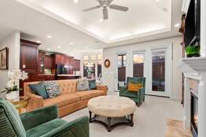 Living room featuring a fireplace, light colored carpet, a chandelier, a ceiling fan, and recessed lighting
