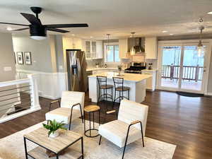 Living room with dark wood-type flooring, a ceiling fan, recessed lighting, and wainscoting