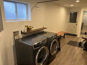 Washroom with dark wood-style floors, washing machine and clothes dryer, and electric panel