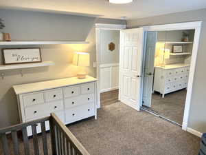 Bedroom with a closet, dark colored carpet, and a crib
