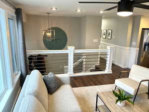 Living area featuring a chandelier, dark wood-style floors, a wainscoted wall, ceiling fan, and recessed lighting