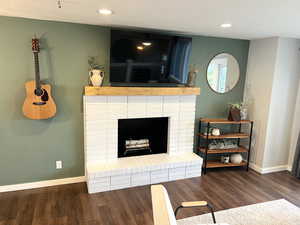 Living room with a fireplace, wood finished floors, and a textured ceiling