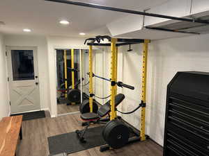 Workout room featuring dark wood-style flooring, recessed lighting, and brick wall