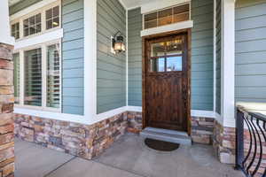 View of exterior entry featuring stone siding and covered porch