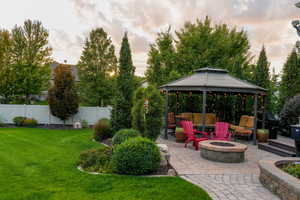 Summer view of yard with a gazebo, a patio area, and an outdoor fire pit