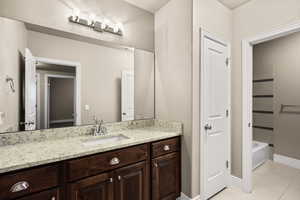 Full bath featuring vanity, light tile patterned floors, and washtub / shower combination