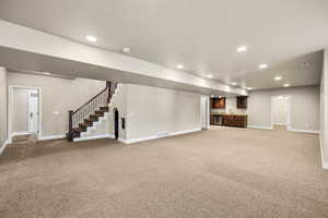 Finished basement featuring stairway, light carpet, wet bar, and recessed lighting