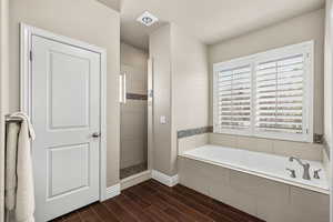 Main bathroom with a bath, a walk in shower, and wood tiled floors