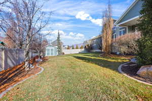 Fenced backyard featuring a storage unit and a residential view