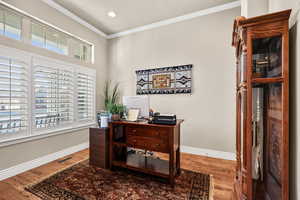 Office area with ornamental molding and wood finished floors
