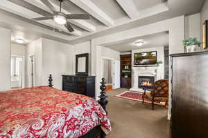 Main bedroom with beam ceiling, carpet, a glass covered fireplace, and a ceiling fan