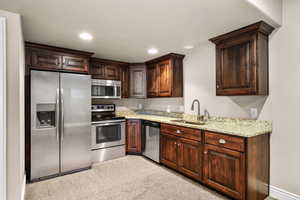 2nd kitchen featuring stainless steel appliances, light stone countertops, dark brown cabinets, recessed lighting, and carpet