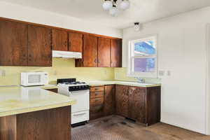 Kitchen with white appliances, light countertops, and under cabinet range hood
