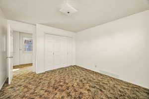 Unfurnished bedroom with carpet, a closet, and a textured ceiling