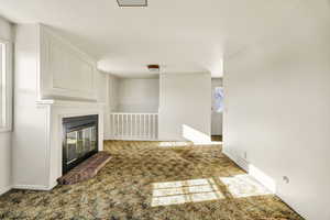 Unfurnished living room with carpet and a glass covered fireplace