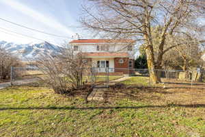 Rear view of house with a fenced front yard, a chimney, a gate, and a mountain view