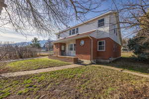 View of front facade with brick siding, a front lawn, and a chimney