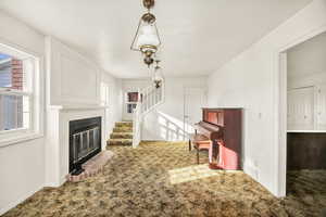 Unfurnished living room with carpet, a fireplace, and stairs