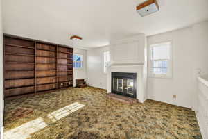 Unfurnished living room with a glass covered fireplace and carpet floors