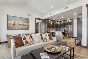 Living room featuring lofted ceiling, light wood-type flooring, and recessed lighting
