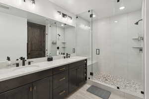 Bathroom featuring double vanity, a stall shower, and recessed lighting
